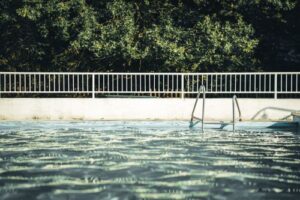 White fence surrounding a swimming pool - Big Florida Fencing