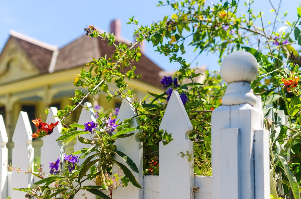 White picket fence with colorful flowers - Big Florida Fencing
